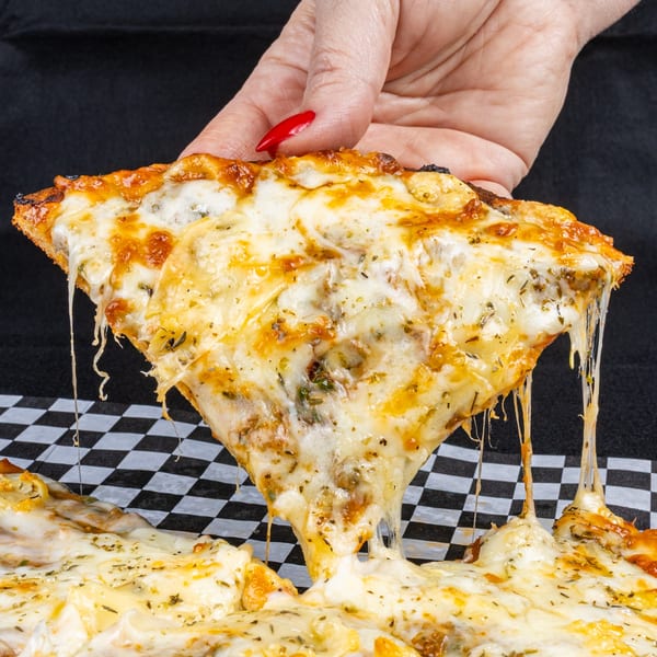 A hand with red nail polish lifts a cheesy pizza slice, stretching melted cheese strands.