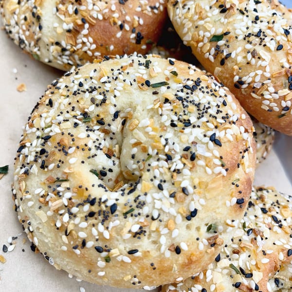 Close-up of several everything bagels, generously topped with seeds, garlic, and onion flakes.