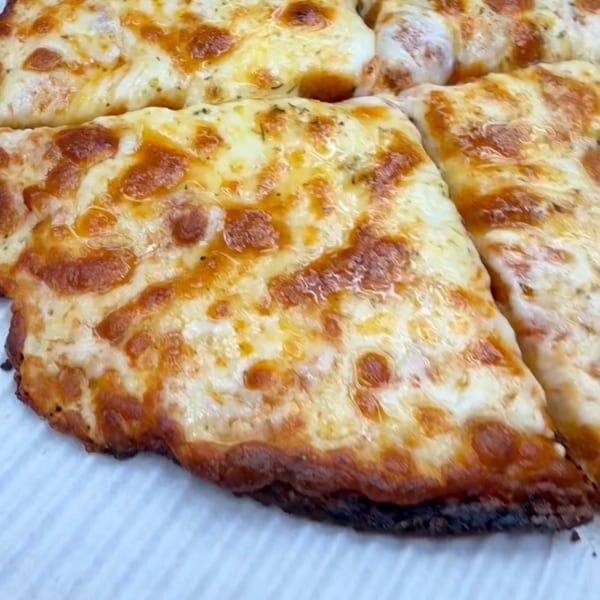 Close-up of a cheesy pizza, cut into slices, with a golden-brown crust.