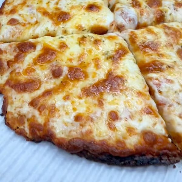 Close-up of a freshly baked cheese pizza, cut into slices, with golden-brown crust and melted cheese.