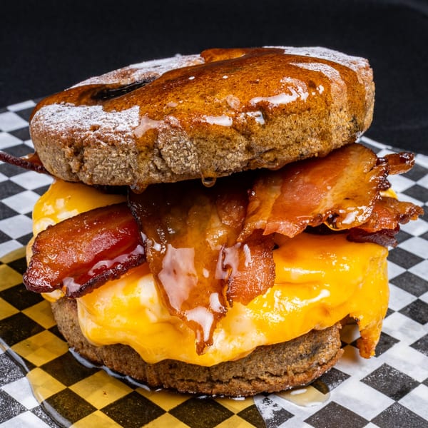 A sweet and savory breakfast sandwich with bacon, egg, and cheese on a honey-glazed donut.